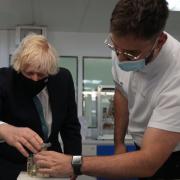 Prime Minister Boris Johnson is shown the workings of ADTM mechanism, which adjusts the reflectors of a satellite, by apprentice engineer Josh Gilberts during a visit to the Airbus Defence and Space plant in Stevenage