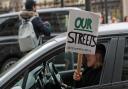 A woman holding a Reclaim the Streets placard out of the passenger window drives past New Scotland Yard in London, the day after clashes between police and crowds who gathered on Clapham Common on Saturday night to remember Sarah Everard. The